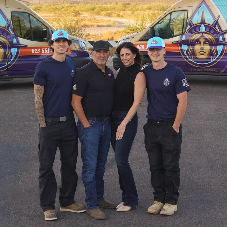 The Ford family standing together in front of two Liberty Plumbing vans in the Arizona desert